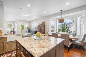 Kitchen featuring dark hardwood / wood-style floors, a textured ceiling, decorative light fixtures, and light stone counters