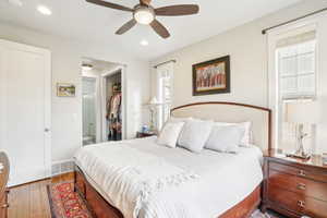 Bedroom featuring hardwood / wood-style flooring, ceiling fan, multiple windows, and a closet