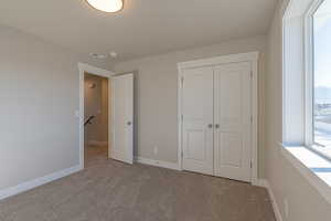 Unfurnished bedroom featuring light carpet and a closet