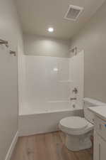 Full bathroom with vanity, hardwood / wood-style flooring, shower / tub combination, and toilet