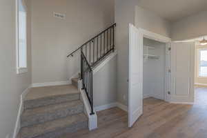 Stairway with hardwood / wood-style flooring and ceiling fan