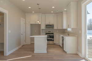 Kitchen with sink, white cabinetry, a center island, pendant lighting, and stainless steel appliances