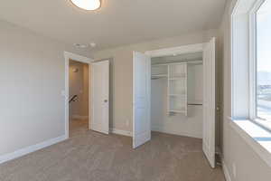 Unfurnished bedroom featuring light carpet and a closet