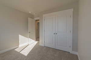 Unfurnished bedroom featuring light carpet and a closet