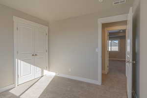 Unfurnished bedroom with light carpet and a closet