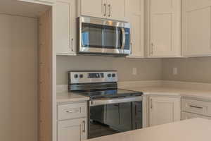 Kitchen featuring stainless steel appliances and white cabinetry