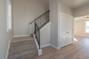 Staircase with hardwood / wood-style flooring and ceiling fan