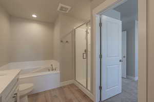 Bathroom with hardwood / wood-style flooring, separate shower and tub, and toilet