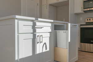 Interior space featuring wood-type flooring, stainless steel appliances, and white cabinets