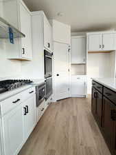 Kitchen featuring white cabinets, light hardwood / wood-style floors, and exhaust hood