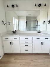 Bathroom with hardwood / wood-style flooring, vanity, and walk in shower