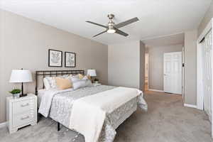 Bedroom with ceiling fan, a closet, and light colored carpet