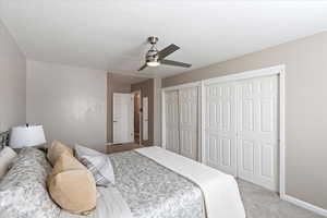 Bedroom featuring ceiling fan, light carpet, and two closets