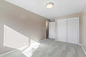 Unfurnished bedroom featuring light colored carpet and a closet