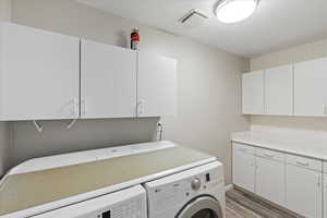 Washroom with cabinets, light hardwood / wood-style floors, and independent washer and dryer