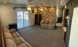 Carpeted living room with washer / clothes dryer, ceiling fan, brick wall, and a textured ceiling