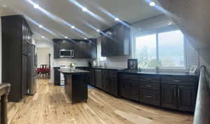 Kitchen featuring appliances with stainless steel finishes, a center island, light hardwood / wood-style flooring, and sink