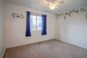 Carpeted empty room featuring ceiling fan