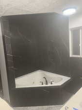 Bathroom featuring a textured ceiling and tiled bath