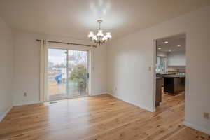 Empty room featuring a chandelier and light hardwood / wood-style flooring