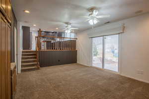 Unfurnished living room featuring ceiling fan, carpet, and a textured ceiling