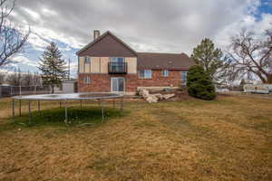 Rear view of house featuring a trampoline, a storage shed, a lawn, and a balcony