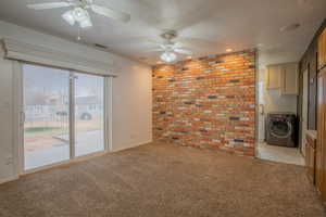 Unfurnished room with brick wall, washer / clothes dryer, ceiling fan, light carpet, and a textured ceiling