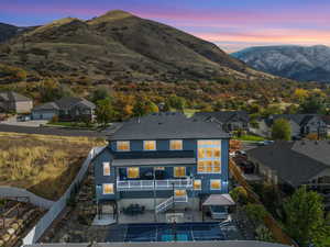 Back house at dusk with a mountain view, a patio, and a balcony