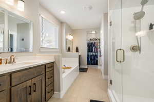 Bathroom with independent shower and bath, vanity, and tile patterned flooring, his & her walk-in closet