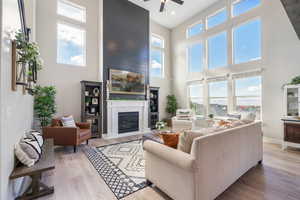 Living room with a high ceiling, light LVP flooring, and plenty of natural light, gas log fireplace