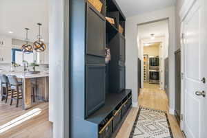 Mudroom featuring light LVP flooring, built-in custom shelving