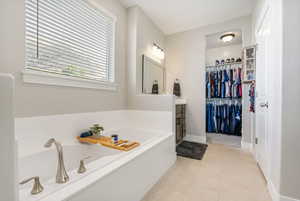 Primary suite bathroom with tile patterned flooring, vanity, and a bathing tub separate from shower, his & her walk-in closets