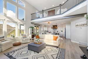 Living room featuring light LVP floors and a towering ceiling, natural light