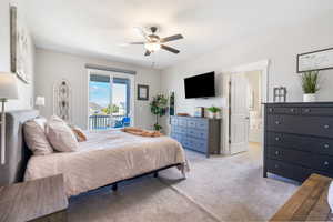 Carpeted primary suite featuring access to outside balcony, ceiling fan, and connected primary suite bathroom