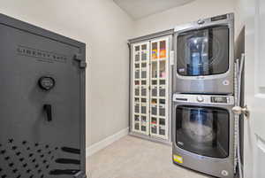 Washroom with stacked washer and dryer and light tile patterned floors