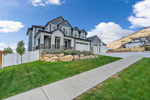 View of front of home featuring a front yard, covered porch, and a garage