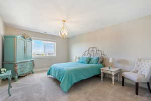 Bedroom with an inviting chandelier and light carpet