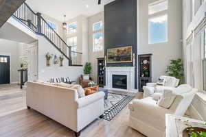 Living room featuring a towering ceiling, plenty of natural light, and light LVP flooring, gas log fireplace