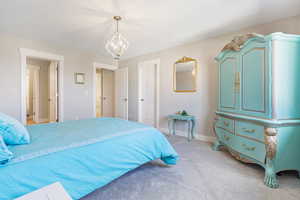 Carpeted bedroom featuring an inviting chandelier