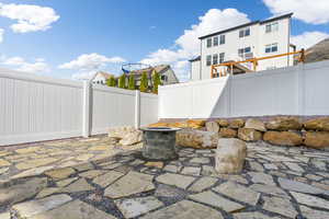 View of patio featuring an outdoor fire pit, vinyl fencing