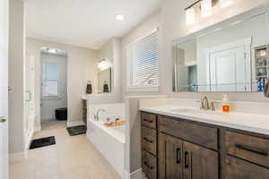 Primary suite bathroom featuring vanity, tile patterned flooring, a washtub, and a healthy amount of sunlight, his & her walk-in closets