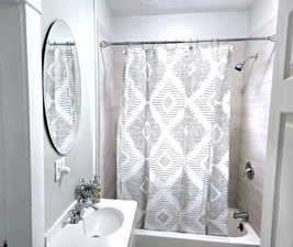 Bathroom with shower / tub combo with curtain, sink, and a textured ceiling