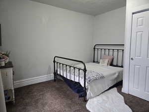 Bedroom featuring a textured ceiling and dark colored carpet