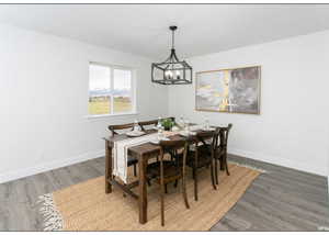 Dining area with dark wood-type flooring and a notable chandelier