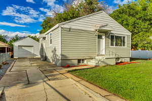 Bungalow-style house with a front yard, a garage, and an outdoor structure