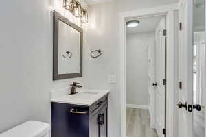 Ensuite bathroom attached to Primary bedroom with hardwood / wood-style floors, vanity, and toilet