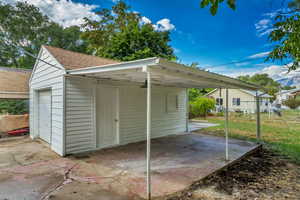 View of outdoor structure with a garage, a yard, and a carport