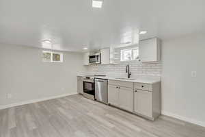 Kitchen featuring a wealth of natural light, appliances with stainless steel finishes, sink, and white cabinets