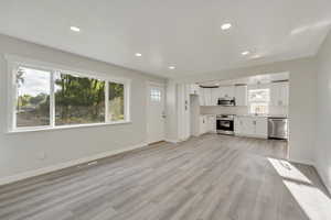 Unfurnished living room with light hardwood / wood-style flooring and sink