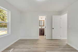 Primary bedroom with ensuite bathroom and light hardwood / wood-style floors